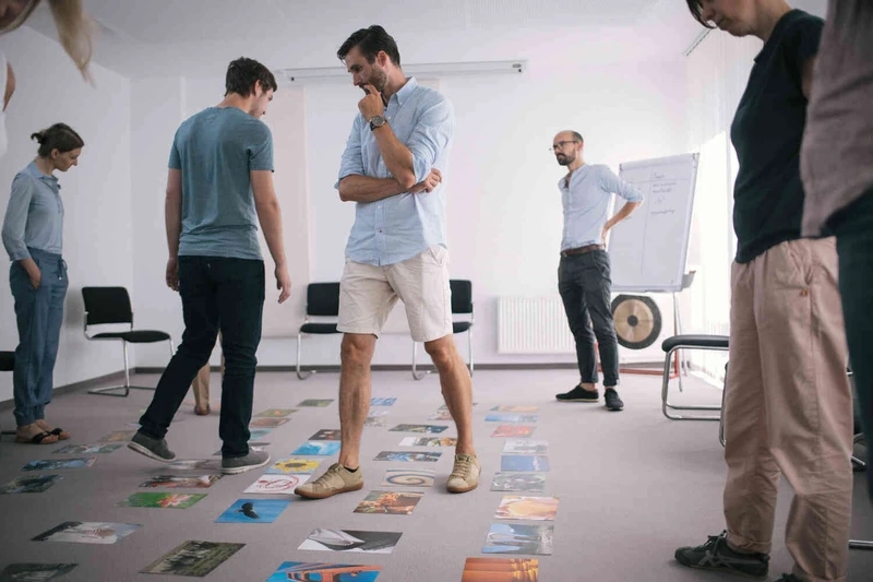 Mann steht in einem raum in mit einer gruppe und schaut auf den boden voller bilder