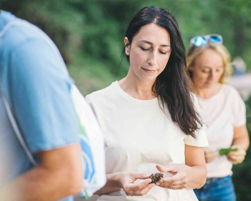 Frau steht drau&szlig;en in einer gruppe und schaut auf eine kastanie.