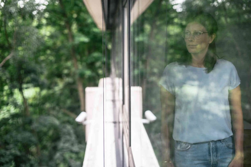 Frau guckt aus dem Fenster in die Natur