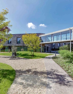 Innenhof der Oberberg Fachklinik D&uuml;sseldorf-Kaarst mit modernen Backsteingeb&auml;uden, begr&uuml;nten Wegen und verglastem Verbindungsgang