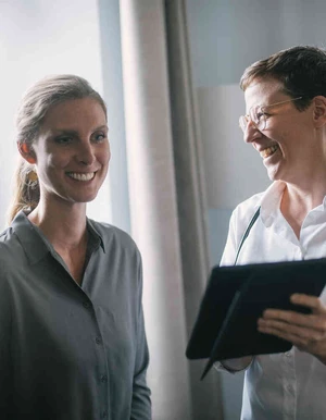 &Auml;rztin im Gespr&auml;ch mit Patientin, beide l&auml;cheln