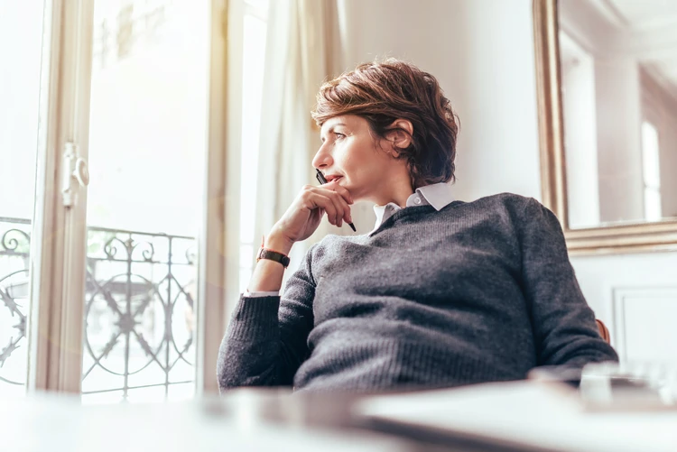 Frau sitzt in einem wei&szlig;en raum und schaut aus dem fenster