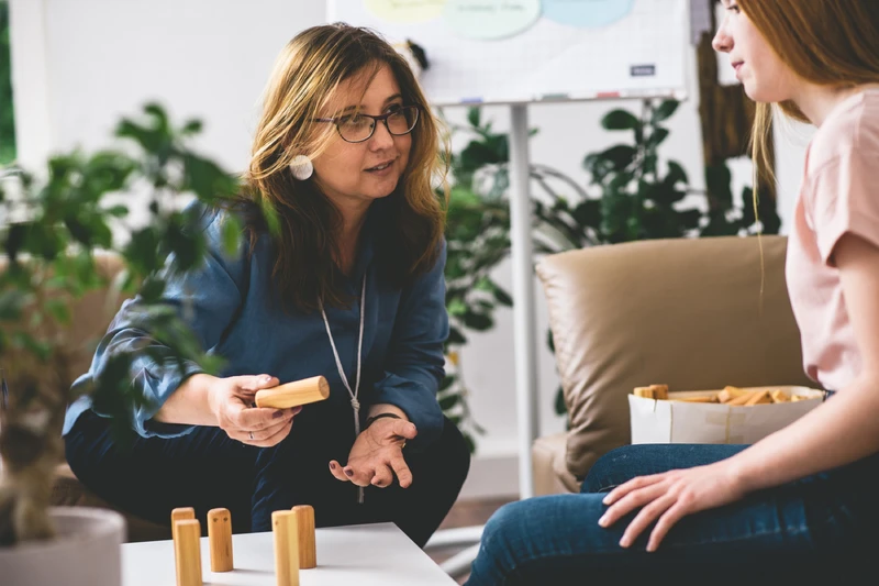 Therapeutin spricht mit Patientin und nutzt holzblock steine.